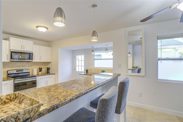 kitchen with decorative backsplash, dark stone counters, appliances with stainless steel finishes, and plenty of natural light