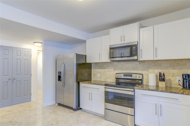 kitchen featuring white cabinetry, dark stone counters, stainless steel appliances, and backsplash