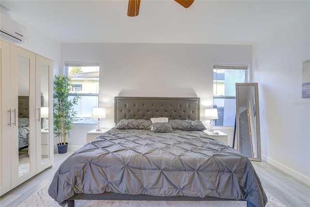 bedroom featuring an AC wall unit, light hardwood / wood-style flooring, and ceiling fan