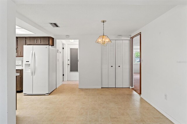 kitchen with white fridge with ice dispenser, pendant lighting, and dark brown cabinetry