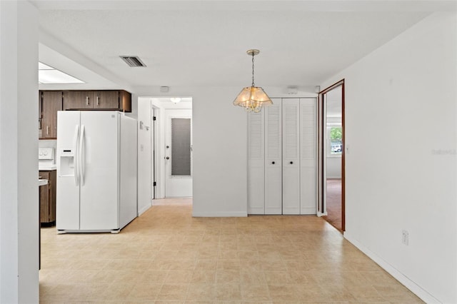 7015 Flaggler Dr, Port Richey, FL 34668 - kitchen with visible vents, white fridge with ice dispenser, light floors, dark brown cabinetry, and decorative light fixtures