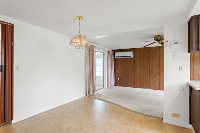 spare room featuring ceiling fan, wooden walls, a textured ceiling, and a wall unit AC