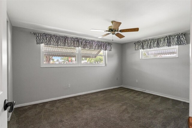 unfurnished room with ceiling fan and dark colored carpet