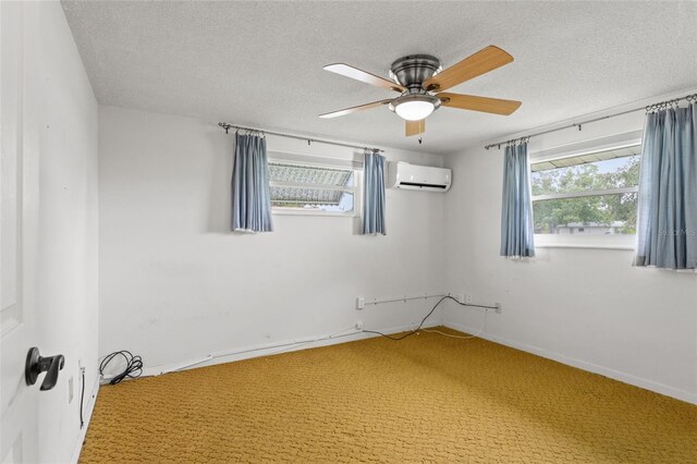 spare room with a wealth of natural light, an AC wall unit, a textured ceiling, and carpet flooring