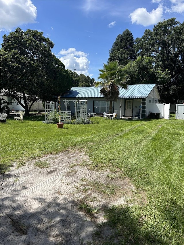 view of front of home with metal roof, a front yard, and fence