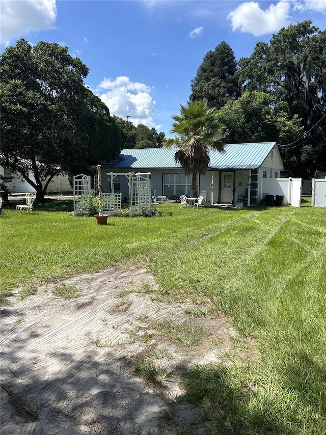 exterior space with fence, metal roof, and a front yard