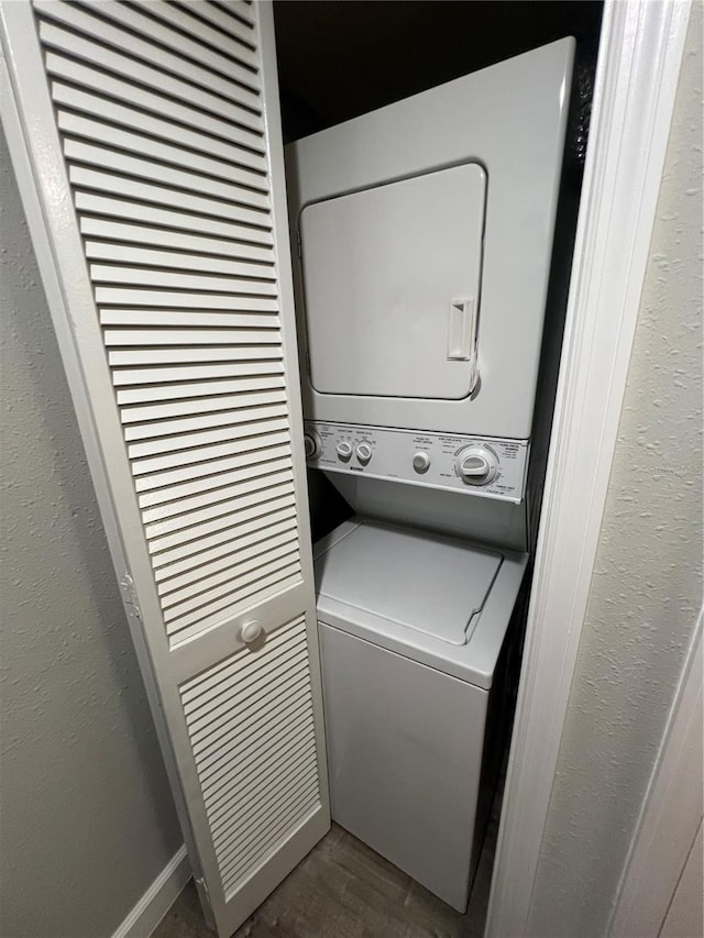 clothes washing area with stacked washing maching and dryer and wood-type flooring