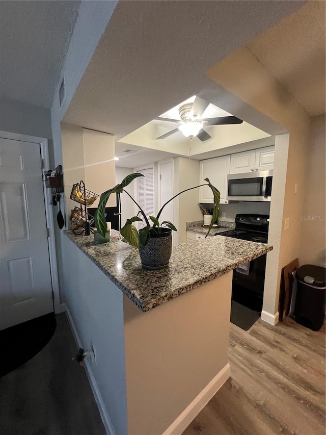 kitchen featuring light hardwood / wood-style floors, black range with electric stovetop, white cabinets, kitchen peninsula, and ceiling fan