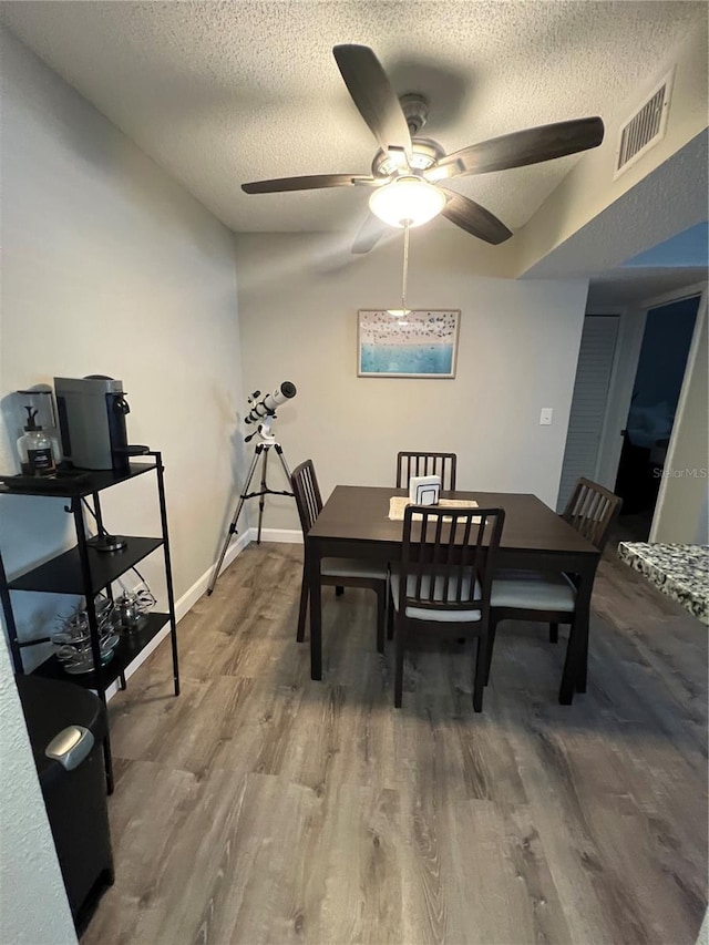 dining room with a textured ceiling, ceiling fan, and hardwood / wood-style floors