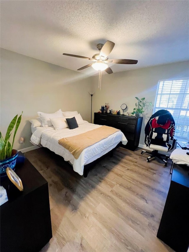 bedroom with a textured ceiling, light hardwood / wood-style flooring, and ceiling fan