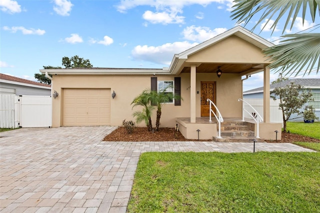 view of front facade with decorative driveway, stucco siding, fence, a garage, and a front lawn