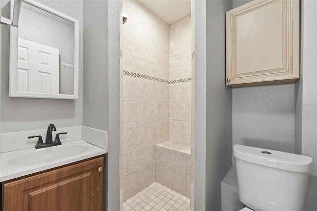 bathroom with a textured wall, a stall shower, vanity, and toilet