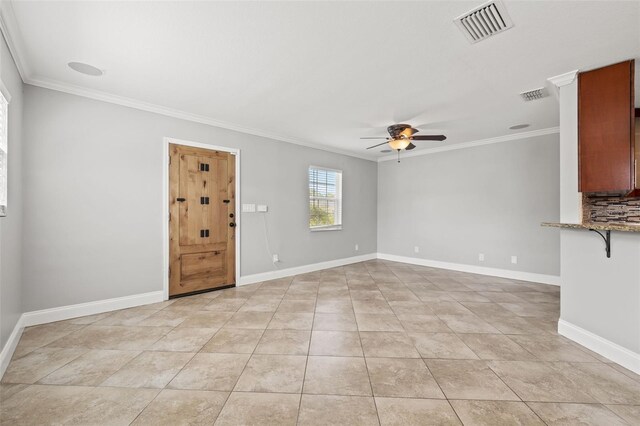 empty room with visible vents, crown molding, and baseboards