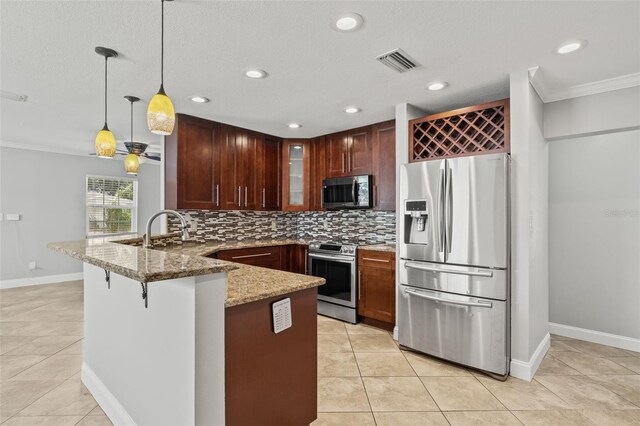 kitchen with light stone counters, stainless steel appliances, a peninsula, visible vents, and backsplash