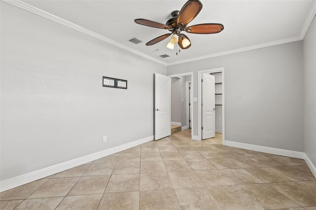 unfurnished bedroom with baseboards, visible vents, ceiling fan, ornamental molding, and a spacious closet