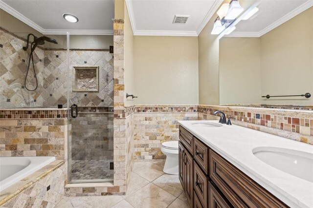 bathroom featuring tile walls, toilet, ornamental molding, a stall shower, and a sink