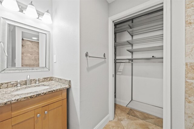 bathroom with tile patterned floors, baseboards, and vanity