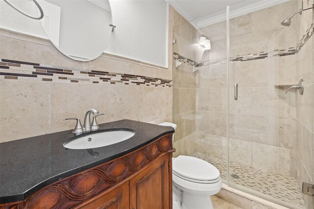 bathroom featuring toilet, tile walls, vanity, a stall shower, and crown molding