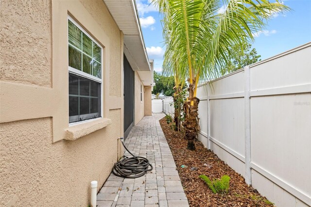 view of side of property featuring a fenced backyard and stucco siding