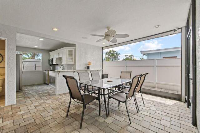 dining space with a textured ceiling, a textured wall, brick floor, recessed lighting, and a ceiling fan