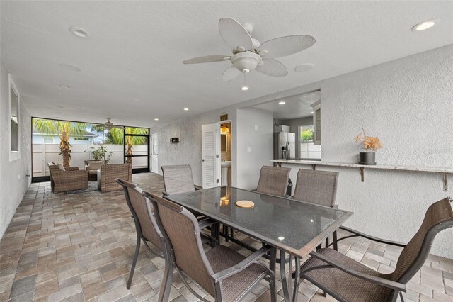 dining space with recessed lighting, plenty of natural light, stone finish flooring, and a textured wall