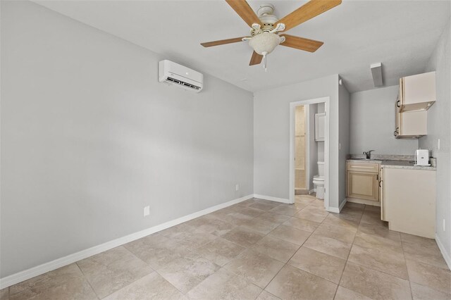 interior space featuring baseboards, connected bathroom, ceiling fan, an AC wall unit, and a sink