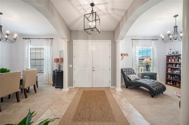 foyer entrance featuring a chandelier, arched walkways, light carpet, and decorative columns