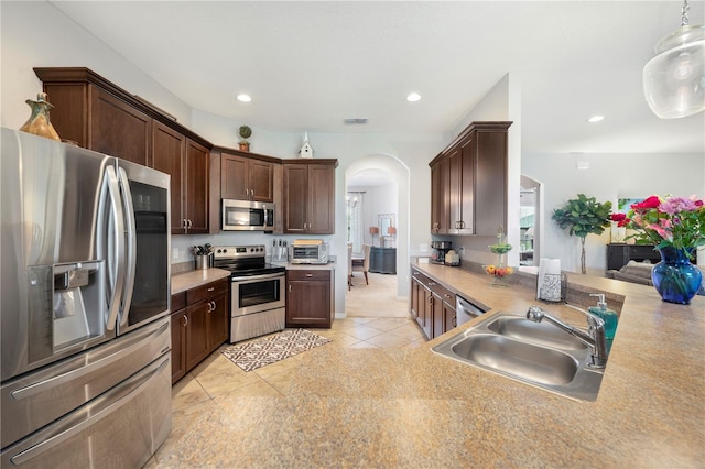 kitchen featuring light tile patterned flooring, dark brown cabinets, hanging light fixtures, sink, and appliances with stainless steel finishes