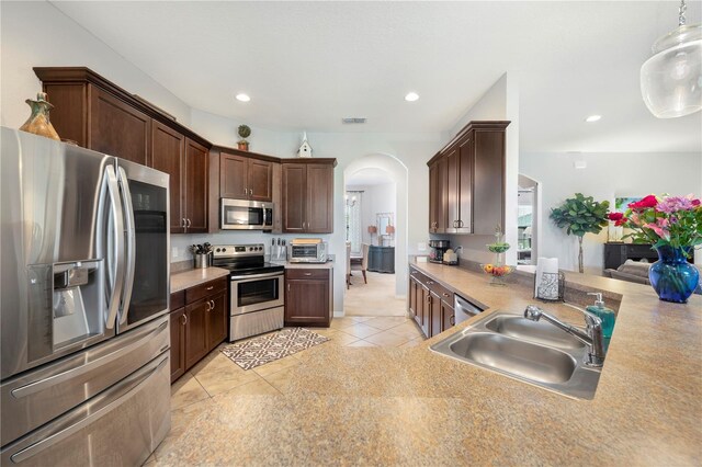 kitchen featuring a sink, stainless steel appliances, arched walkways, and light countertops