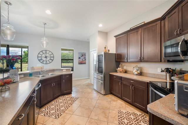 kitchen featuring appliances with stainless steel finishes, a sink, hanging light fixtures, and dark brown cabinetry