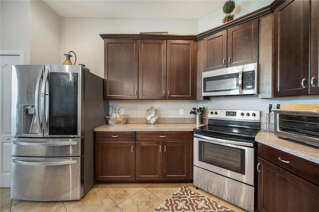 kitchen featuring a toaster, light tile patterned floors, light countertops, appliances with stainless steel finishes, and dark brown cabinets