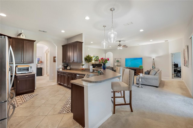 kitchen with ceiling fan, light carpet, sink, kitchen peninsula, and a kitchen breakfast bar