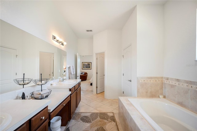 bathroom with vanity, tiled tub, and tile patterned flooring