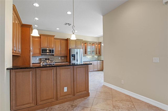 kitchen featuring dark stone countertops, light tile patterned floors, decorative backsplash, hanging light fixtures, and appliances with stainless steel finishes