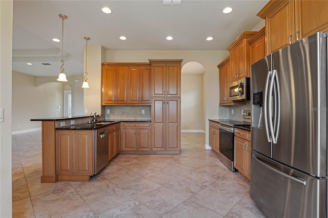 kitchen featuring kitchen peninsula, sink, decorative backsplash, hanging light fixtures, and appliances with stainless steel finishes