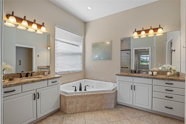 bathroom featuring tiled tub, vanity, and tile patterned flooring