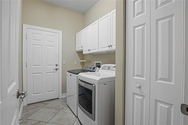 clothes washing area with washing machine and clothes dryer, cabinets, and light tile patterned flooring