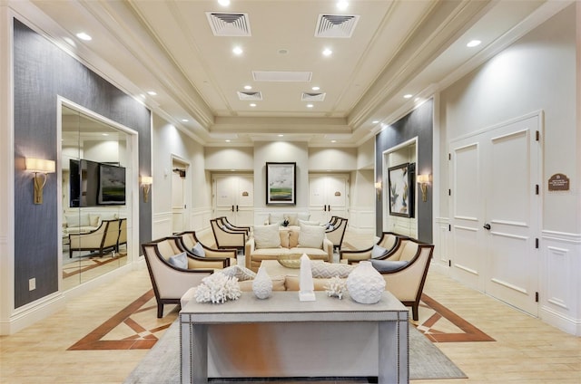 living room featuring a raised ceiling, ornamental molding, and light wood-type flooring