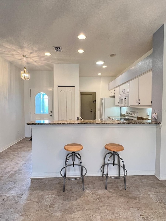 kitchen with decorative light fixtures, a kitchen breakfast bar, kitchen peninsula, white appliances, and white cabinets