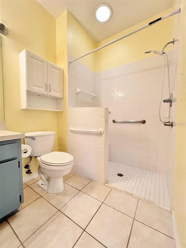 bathroom with vanity, toilet, tile patterned flooring, and a tile shower