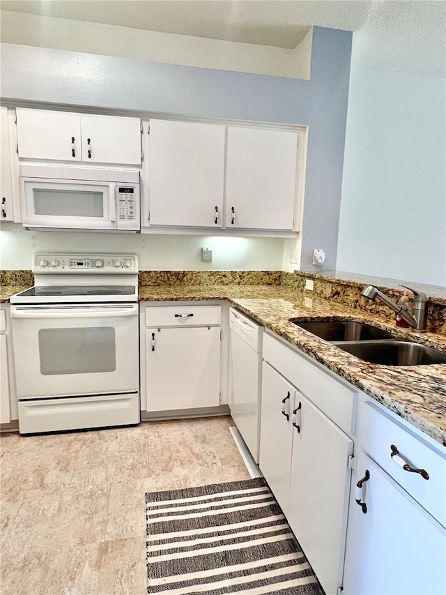 kitchen with stone counters, white cabinetry, sink, and white appliances