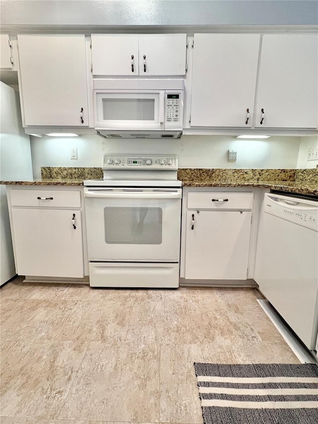 kitchen with white cabinetry, white appliances, and dark stone countertops