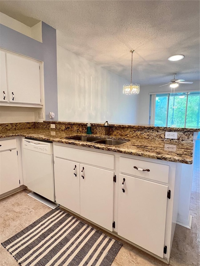 kitchen with pendant lighting, white cabinetry, sink, dark stone countertops, and white dishwasher