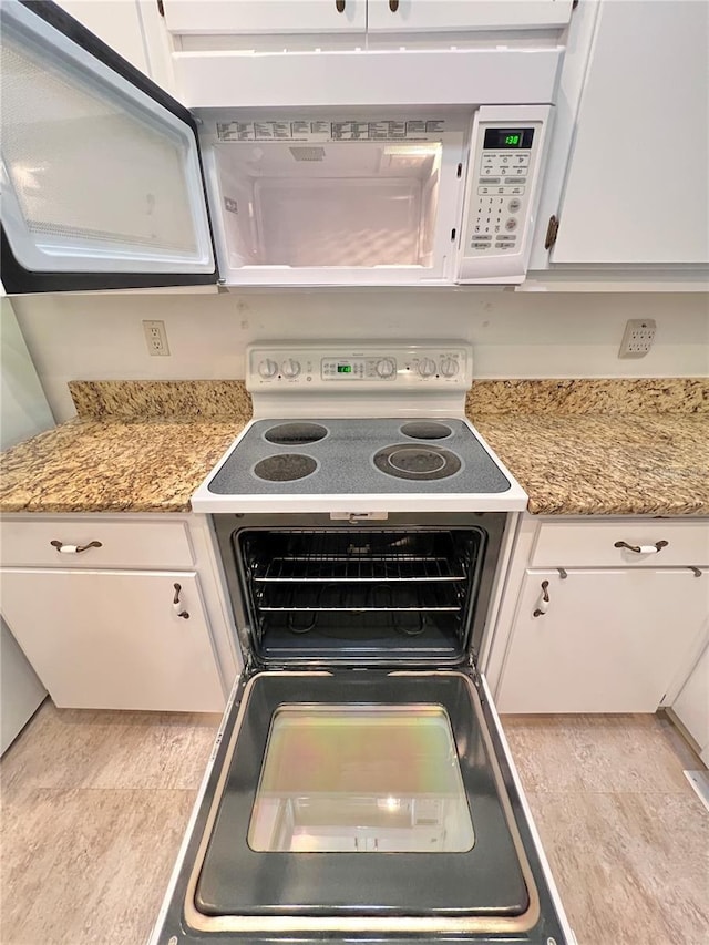 kitchen featuring white cabinetry, white appliances, and light stone countertops