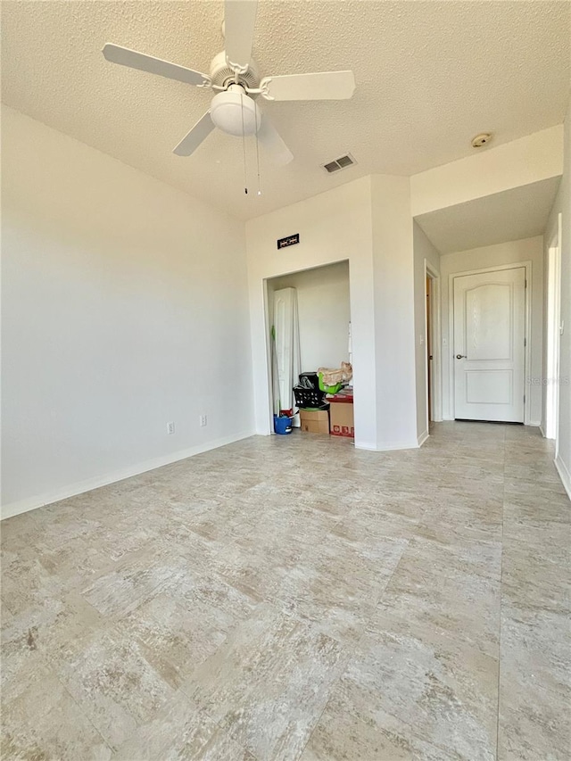 empty room with ceiling fan and a textured ceiling