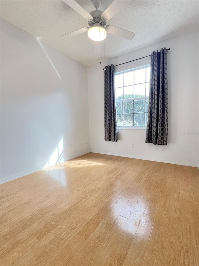 empty room with ceiling fan, light hardwood / wood-style flooring, and a textured ceiling