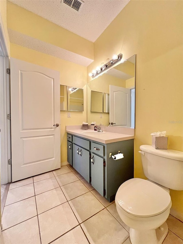 bathroom with vanity, a textured ceiling, tile patterned floors, and toilet