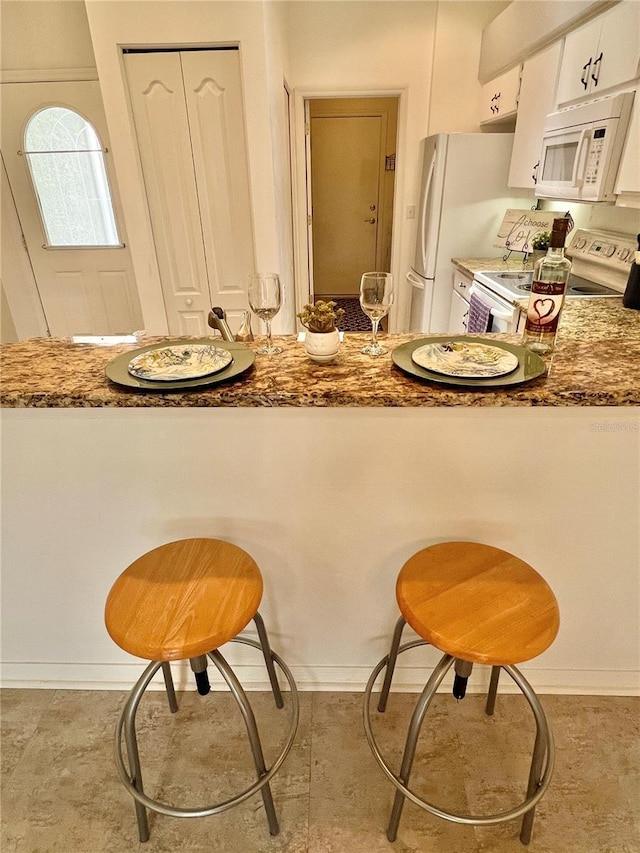 761 Tremont Greens Ln Unit 61, Sun City Center, FL 33573 - kitchen featuring white appliances, a kitchen breakfast bar, white cabinetry, and stone counters
