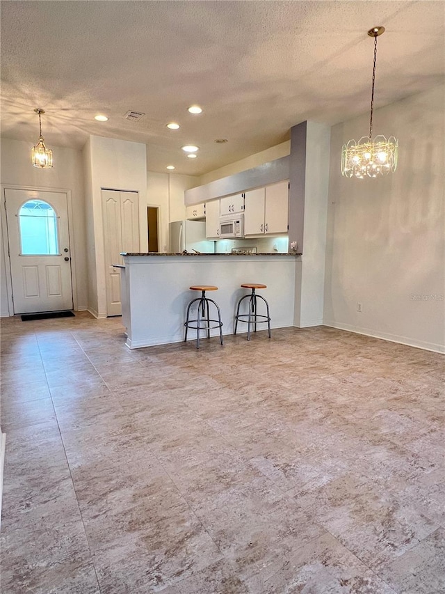 761 Tremont Greens Ln Unit 61, Sun City Center, FL 33573 - kitchen featuring white appliances, a chandelier, dark countertops, a textured ceiling, and hanging light fixtures