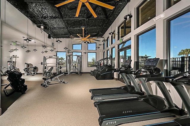 gym featuring a ceiling fan and a towering ceiling